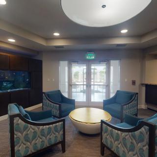 A cozy lobby area with elegant chairs arranged around a central table, well-lit by overhead lighting.