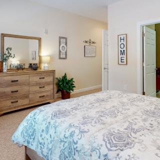 A cozy and inviting bedroom featuring a stylish dresser, a decorative mirror, and soft bedding.