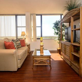 A cozy living room with wooden furniture, a sofa, and a television, bathed in natural sunlight.
