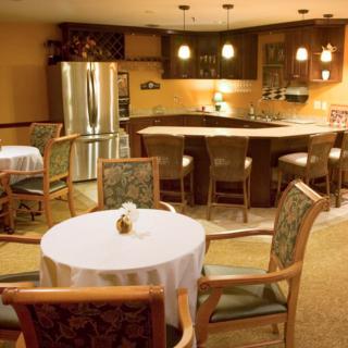 A cozy dining area with a round table and chairs, adjacent to a kitchen featuring a bar counter and stainless steel refrigerator.