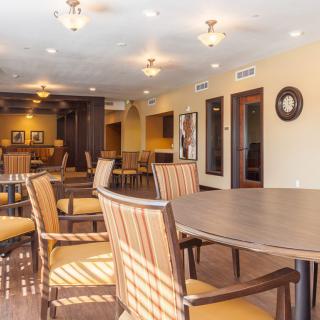 A spacious dining area with wooden tables and chairs, warmly lit by ceiling fixtures.