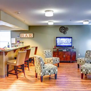 A cozy living space with a bar area and comfortable seating, featuring a television mounted on the wall.