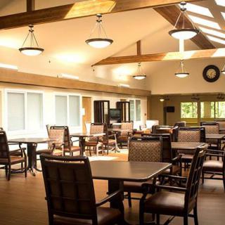 A well-lit dining area with multiple tables and chairs arranged neatly in a spacious room.