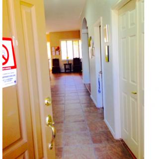 A well-lit corridor in a home with tiled flooring and multiple doors.