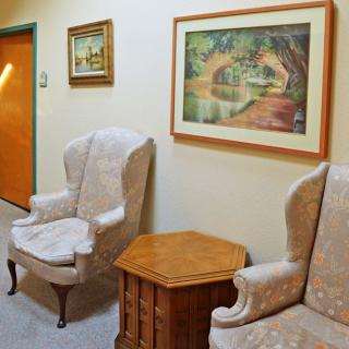 A cozy hallway with two armchairs, a wooden side table, and framed artwork on the wall.