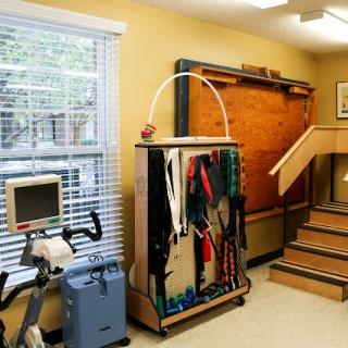 A well-equipped rehabilitation therapy room featuring exercise equipment and a staircase.