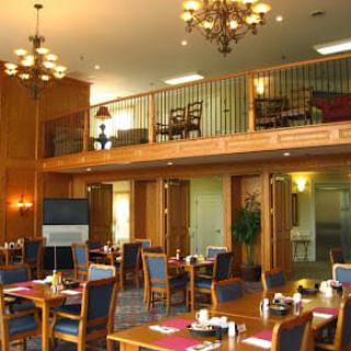 A spacious dining area with elegant chandeliers and neatly arranged tables and chairs.