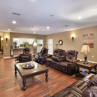 A spacious living room with leather couches, a wooden coffee table, and warm lighting.