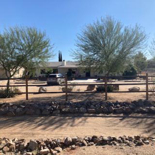 A serene view of a desert house surrounded by trees and a rustic fence.