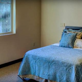 A cozy bedroom with a single bed adorned with blue bedding and a window on the side.