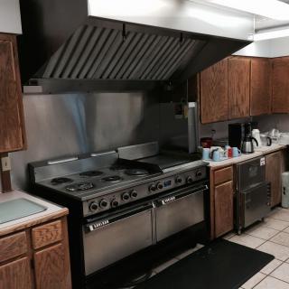 A commercial kitchen setup featuring a large stove and oven with wooden cabinets and a range hood.