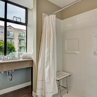 A modern and minimalist bathroom featuring a shower with a curtain, a window with a view, and a sleek sink.