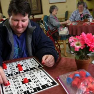 A person playing bingo at a table with flowers and bingo markers.