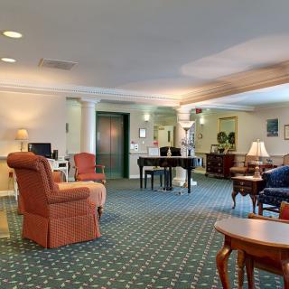 A spacious and well-furnished living room featuring comfortable seating, a piano, and elegant decor.