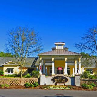 A picturesque building entrance surrounded by lush landscaping and clear blue skies.