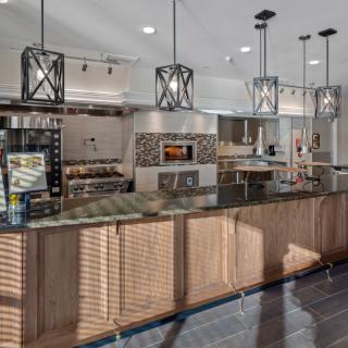 A modern kitchen with wood cabinets, a large island counter, and stainless steel appliances.