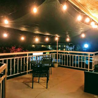 A cozy outdoor patio at night, illuminated by warm string lights.