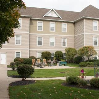 A three-story residential building with well-maintained landscaping and outdoor seating.