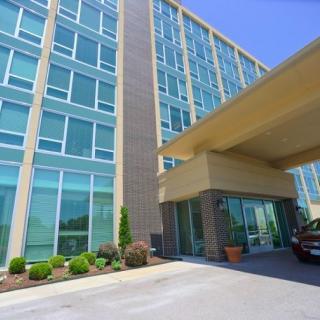 A modern hotel building with large glass windows and a covered entrance.