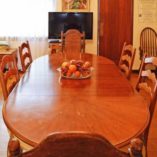 A cozy dining room featuring a wooden table with chairs and a fruit bowl centerpiece.