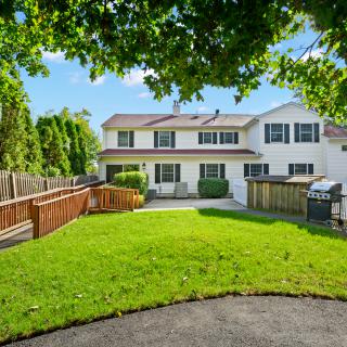 A suburban house with a well-maintained lawn and surrounding trees.