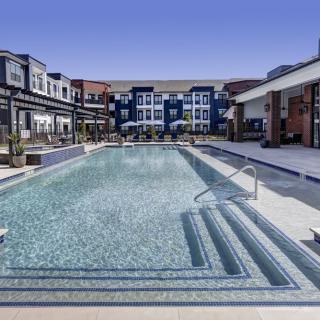A luxurious residential complex with a large outdoor swimming pool and modern architecture.