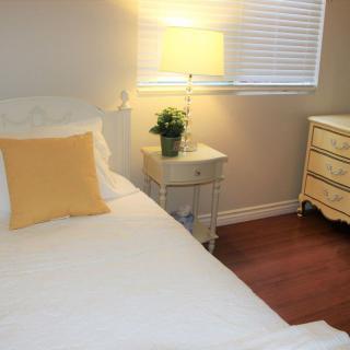 A cozy bedroom with a white bed, yellow pillow, and soft lighting from a lamp on the nightstand.