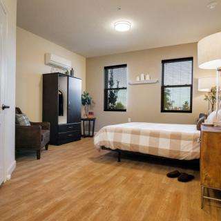 A modern and cozy bedroom featuring a comfortable bed with a checkered duvet, wooden flooring, and stylish decor.