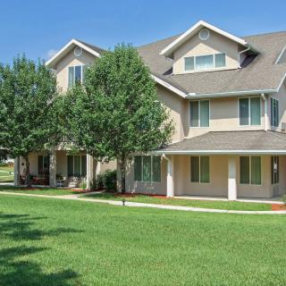 A suburban residential building with a well-kept lawn and trees in front.