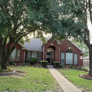 A charming brick house surrounded by lush greenery.