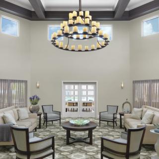 A spacious and elegant living room with a central chandelier and comfortable seating arrangement.