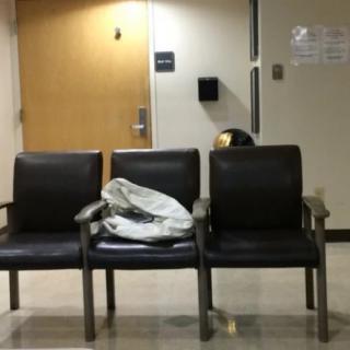 A quiet waiting area with three chairs, featuring a jacket draped over one chair in a hallway.