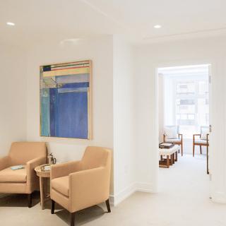 A stylish and modern waiting room featuring comfortable seating and contemporary artwork.