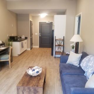 A cozy apartment living area with a sofa, coffee table, and kitchenette.