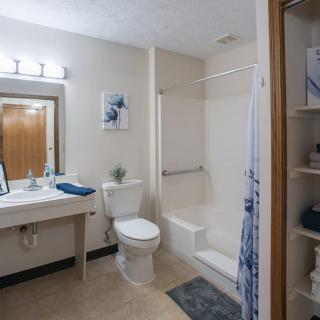 A modern bathroom featuring a shower, toilet, and sink with mirrored vanity and neatly arranged towels.