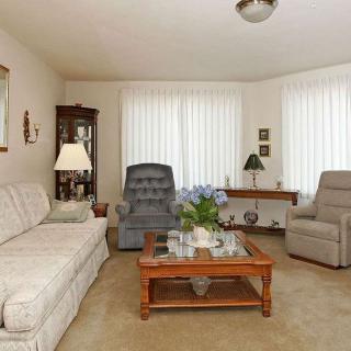 A cozy living room featuring a sofa, armchairs, and a wooden coffee table on a beige carpet.
