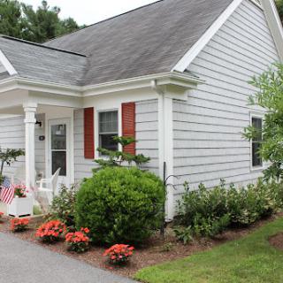 A charming residential house with a well-maintained garden and colorful flowers in the front yard.