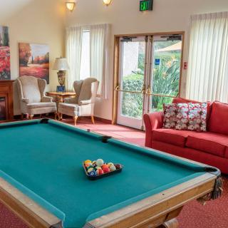A cozy living room with a pool table, comfortable seating, and warm lighting.