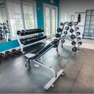 A gym with rows of dumbbells and a workout bench, set up for strength training.