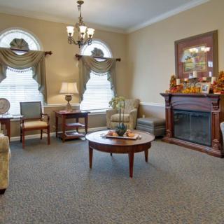 A traditional living room featuring elegant furniture, a decorative fireplace, and classic drapes.