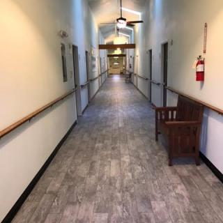 A long, well-lit hallway with a bench and fire extinguisher on the side.