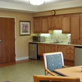 A well-lit kitchen area with wooden cabinets, a table and chairs, and various appliances.