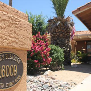 A charming residential entrance featuring flourishing plants, palm trees, and a clearly displayed address sign.