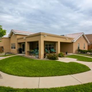 A suburban house with a well-maintained lawn and pathway under a cloudy sky.