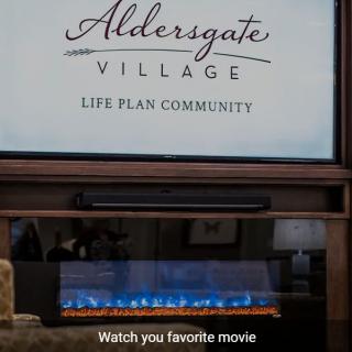 An advertisement for Aldersgate Village Life Plan Community displayed above a cozy fireplace.