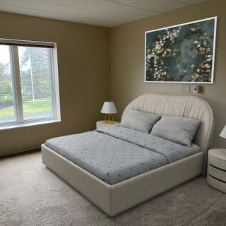 A modern bedroom featuring a large bed, cozy lighting, and stylish artwork.