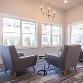 A modern, minimalist living room with comfortable chairs and large windows.