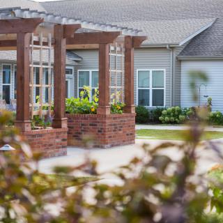 A charming brick gazebo in a residential area surrounded by greenery.
