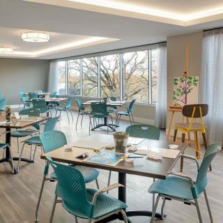 A modern dining area with teal-colored chairs and large windows, offering a bright and inviting atmosphere.