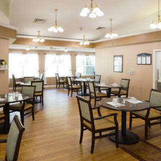 A well-lit dining room with neatly arranged tables and chairs.